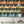 Mixology wallpaper by Brand McKenzie in black, close-up of shelves of colourful bottles
