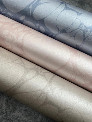 Moucheté wallpaper by House of Amitié in pink, partly unrolled roll showing soft marbled spots