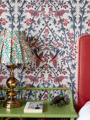 Palamara wallpaper by Deus ex Gardenia in blue and red, mirrored birds and flowers in a bedroom