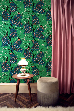 Peacock wallpaper by Dupenny in green, peacocks in branches in a styled room setting
