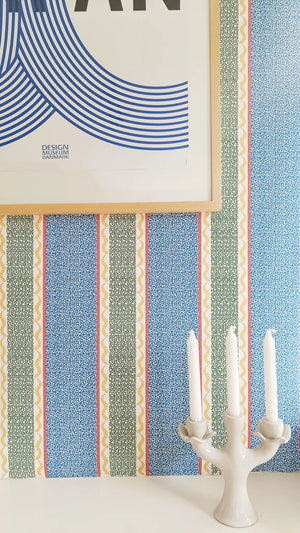 Pio wallpaper by Claire de Quénetain in blue, fine stripes behind a console table