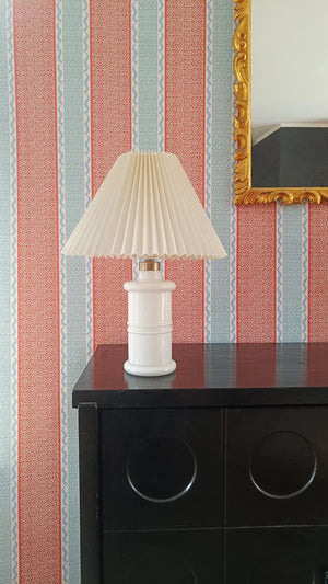Pio wallpaper by Claire de Quénetain in red, fine stripes above a cabinet