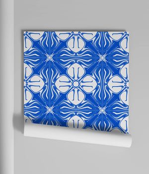 Santorini Tile wallpaper by Liberty James Studio in blue and white behind a sofa in a living room