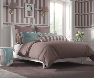 Scallop Lane wallpaper by Liberty James Studio in pink, scalloped stripes behind a bed