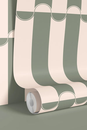 Scallop Lane wallpaper by Liberty James Studio in sage green, partly unrolled roll showing scalloped stripes