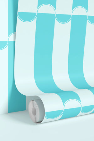 Scallop Lane wallpaper by Liberty James Studio in turquoise and white, partly unrolled roll showing scalloped stripes