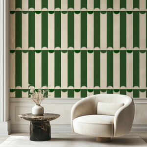 Scallop Lane wallpaper by Liberty James Studio in green, scalloped stripes behind a sofa in a living room