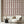 Scallop Lane wallpaper by Liberty James Studio in pink, scalloped stripes behind a sofa in a living room