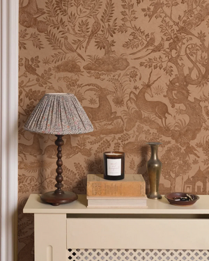Fablewood wallpaper by Deus ex Gardenia in terracotta, a storybook woodland toile above a sideboard