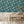 Silk Shades wallpaper by Brand McKenzie in teal, layered silk lampshades behind a dining table