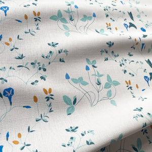 Simone linen by Claire de Quénetain in green and blue, draped, showing a hand-painted floral design