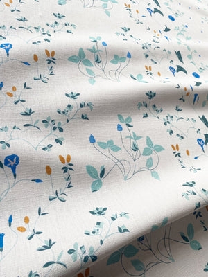 Simone linen by Claire de Quénetain in green and blue, draped, showing a hand-painted floral design