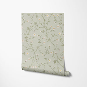 Daisy Chain wallpaper by Studio Le Cocq in pale green, partly unrolled roll showing trailing daisy chains
