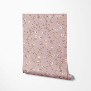 Daisy Chain wallpaper by Studio Le Cocq in pink, partly unrolled roll showing trailing daisy chains