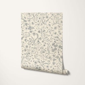 The Lost Garden Cottage wallpaper by Studio Le Cocq in blue, partly unrolled roll showing a dense garden of flowers