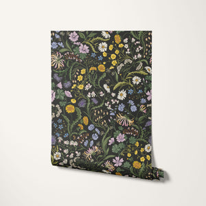 The Lost Garden wallpaper by Studio Le Cocq in black, partly unrolled roll showing a dense garden of flowers