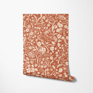 The Lost Garden wallpaper by Studio Le Cocq in terracotta, partly unrolled roll showing a dense garden of flowers