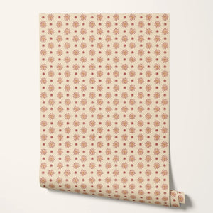 Sunshine Masquerade wallpaper by Annika Reed in cream and red, roll showing sun and mask motifs