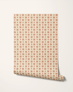 Sunshine Masquerade wallpaper by Annika Reed in cream and red, roll showing sun and mask motifs