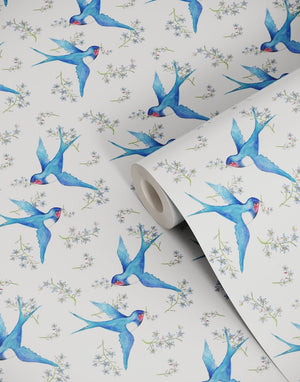 Forget Me Not wallpaper by Seed Home Designs in blue, partly unrolled roll showing scattered forget-me-nots
