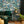 The Art Deco Hills wallpaper by Brand McKenzie in teal, Art Deco hillside scenes behind a sofa in a living room