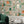 The Cabinet wallpaper by Brand McKenzie in green and amber, close-up of a cabinet of curiosities