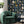 The Cabinet wallpaper by Brand McKenzie in navy, a cabinet of curiosities behind a sofa in a living room