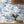 The Mediterranean wallpaper by Brand McKenzie in blue and white, a whitewashed hillside village behind a dining table