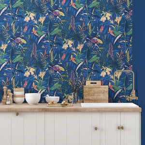 The Tropics wallpaper by Brand McKenzie in blue, tropical leaves and birds above a sideboard