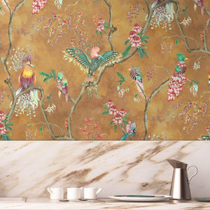 Birds in Paradise wallpaper by Brand McKenzie in gold, tropical birds on blossoming branches above a sideboard