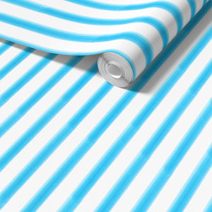 Blue Watercolour Beach Stripe wallpaper by Seed Home Designs in blue and white, partly unrolled roll showing
