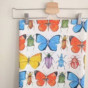 Beetle and Butterfly fabric by Seed Home Designs in red, blue and green in a styled room setting