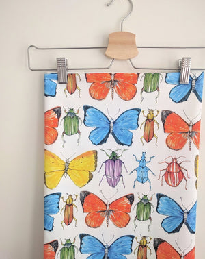 Beetle and Butterfly fabric by Seed Home Designs in red, blue and green in a styled room setting