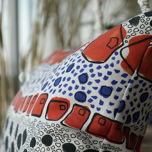 Cellular linen by Bethie Tricks in orange and black, bold cell shapes made into a cushion