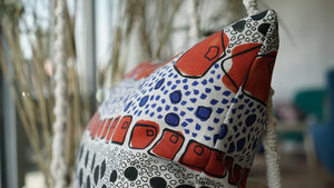 Cellular linen by Bethie Tricks in orange and black, bold cell shapes made into a cushion