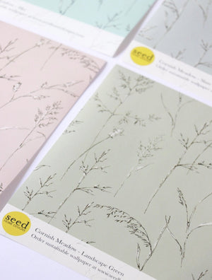 Cornish Meadow wallpaper by Seed Home Designs in grey, partly unrolled roll showing fine meadow grasses