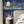 Creature Club wallpaper by Brand McKenzie in blue, animals on a checkerboard stage behind a bed