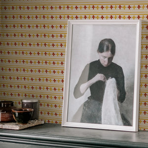 Cross Stitch wallpaper by Annika Reed in orange and red, cross-stitch motifs above a sideboard