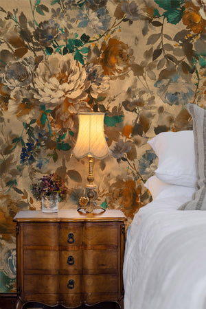 Bridie wallpaper by Curate Space in warm autumn orange, oversized painterly blooms in a bedroom with a wooden bedside chest and table lamp