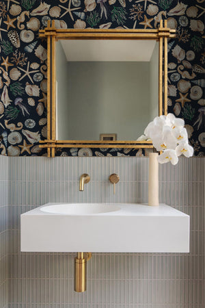 Charlotte Curate Space wallpaper in midnight blue, hand-painted seashells and starfish in a modern bathroom with a gold-framed mirror