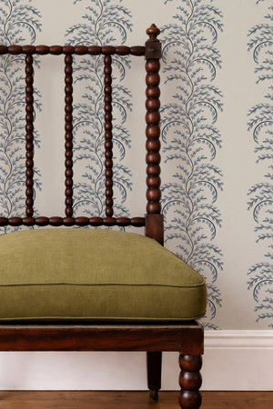 Edie wallpaper by Curate Space in blue, arching fern fronds in vertical columns behind a spindle chair with a green cushion