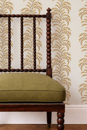 Edie wallpaper by Curate Space in ochre yellow, arching fern fronds in vertical columns behind a spindle chair with a green cushion