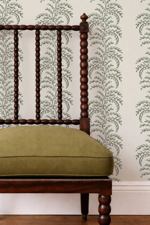 Edie wallpaper by Curate Space in soft green, arching fern fronds in vertical columns behind a spindle chair with a green cushion
