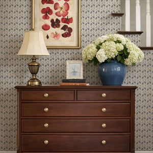 Etta wallpaper by Curate Space in navy, small floral sprigs behind a wooden chest of drawers on a staircase landing