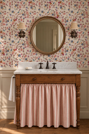 Little Freya wallpaper by Curate Space in soft pink, small abstract flowers and leaves in a bathroom with a skirted sink and round mirror