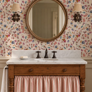 Little Freya wallpaper by Curate Space in soft pink, small abstract flowers and leaves in a bathroom with a round mirror and a wooden vanity