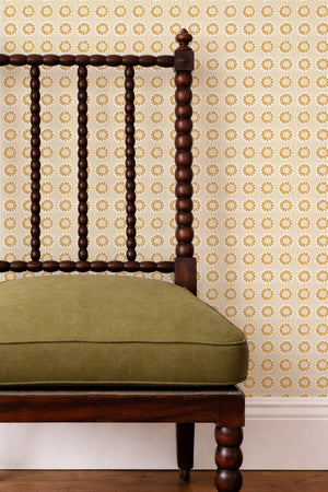 Mabel wallpaper by Curate Space in yellow, small rosette motifs behind a spindle chair with a green cushion