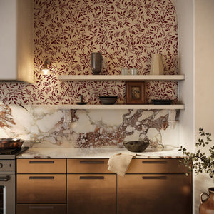 Marni wallpaper by Curate Space in rust orange, sweeping leafy vines in a kitchen above a marble splashback