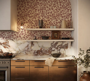 Marni wallpaper by Curate Space in rust orange, sweeping leafy vines in a kitchen above a marble splashback