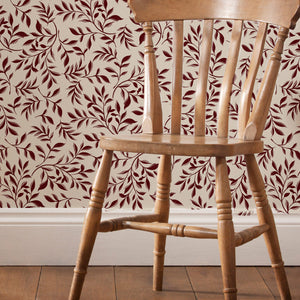 Marni wallpaper by Curate Space in rust orange, sweeping leafy vines in a room with a wooden chair